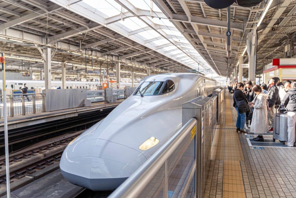 Shinkansen bullet train with passengers waiting on a station platform in Japan
