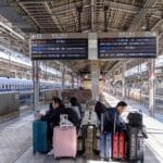 Travelers with suitcases waiting beside a Shinkansen train in Japan