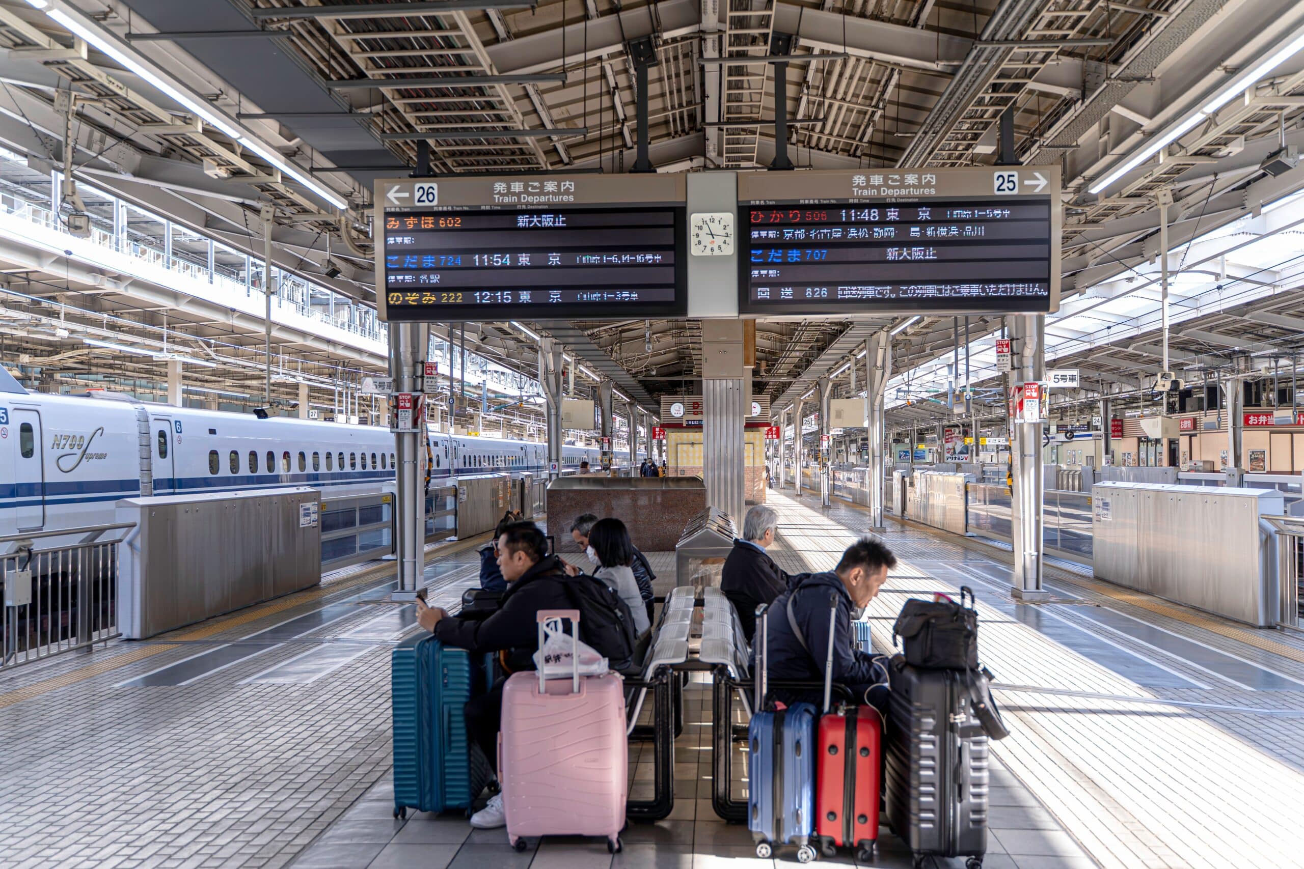 Travelers with suitcases waiting beside a Shinkansen train in Japan