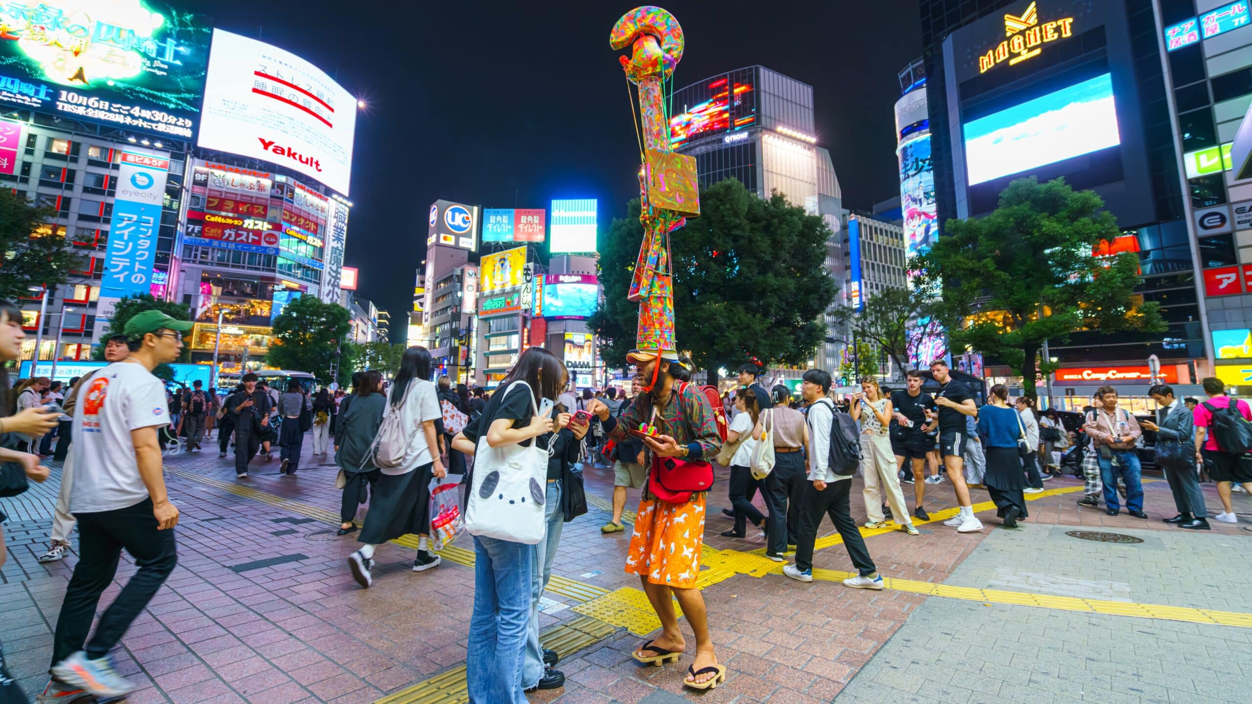 Busy Shibuya district in Tokyo at night with travelers and illuminated buildings