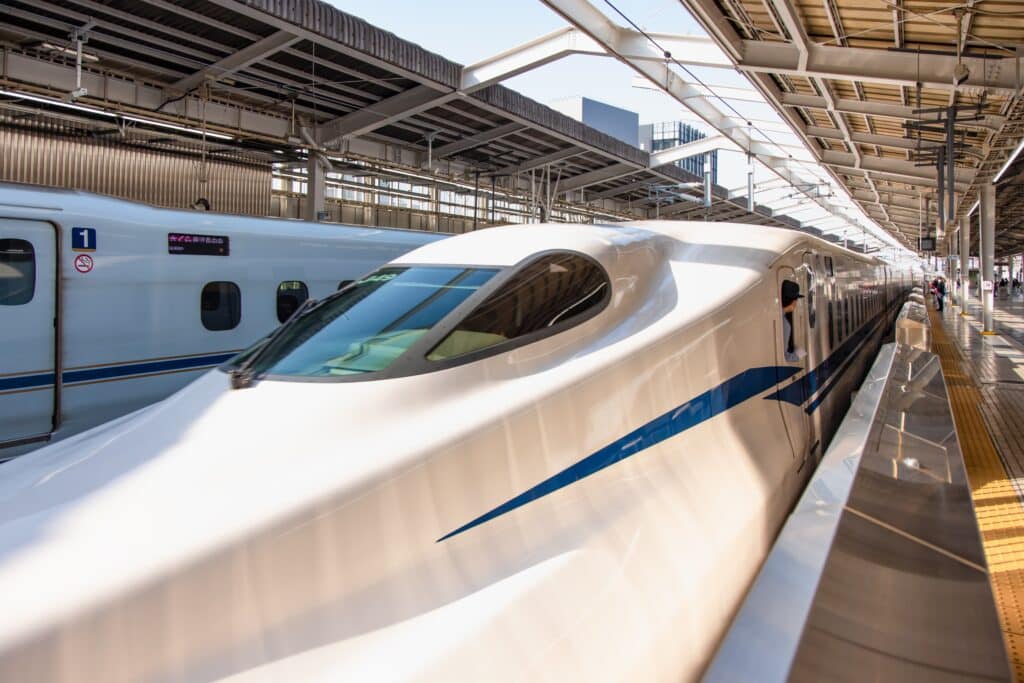 White and blue Shinkansen bullet train standing at a Japanese railway station platform