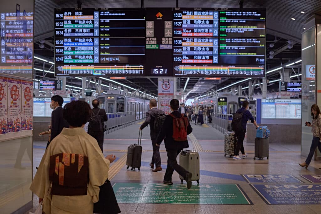 Travelers with suitcases beside a Shinkansen train in Japan