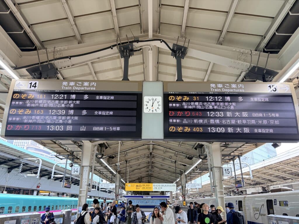 Shinkansen departure boards displaying Nozomi and Hikari train services at a Japanese railway station