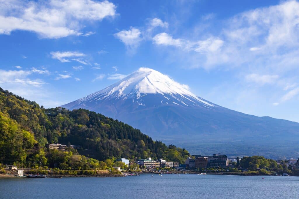 Mount Fuji towering above lakeside buildings and the waters of Lake Kawaguchiko