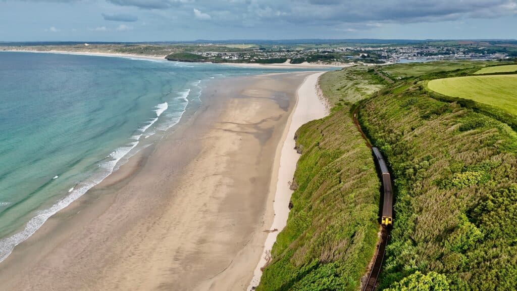 Train travelling beside a sandy beach on the Cornwall coast