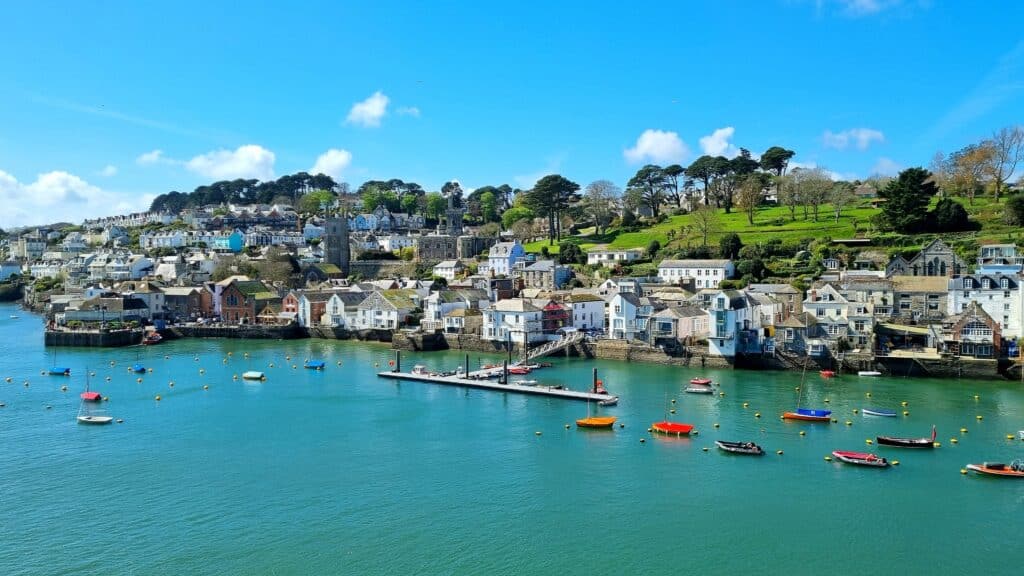 Fowey harbour in Cornwall, with colourful boats, waterfront houses and wooded hills overlooking the estuary