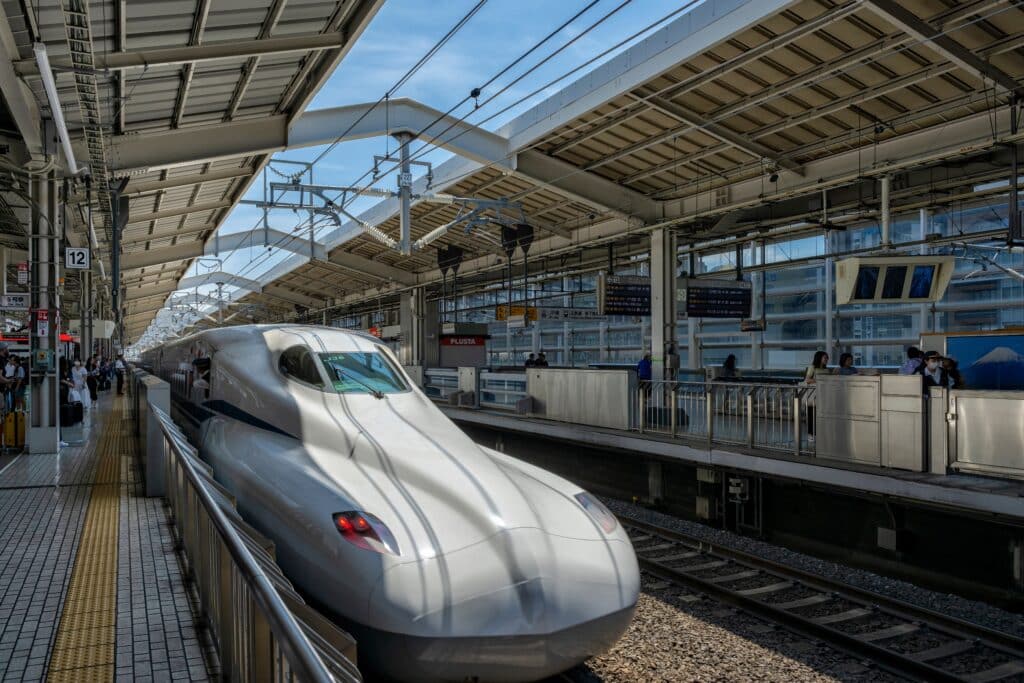 White Shinkansen bullet train waiting beside a platform at a Japanese railway station