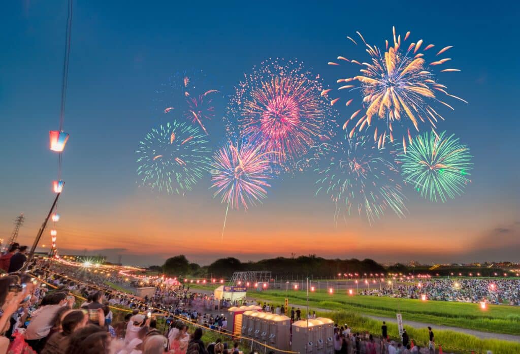 Colorful fireworks illuminating the evening sky above spectators at a Japanese summer festival