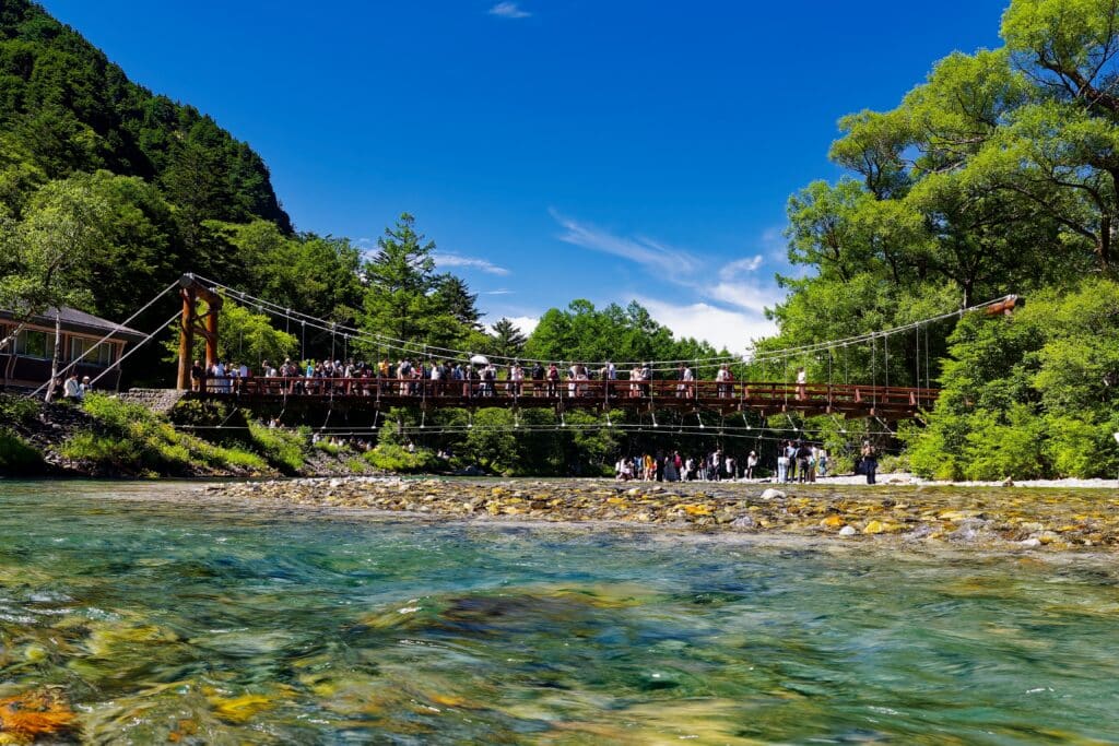 Kappa Bridge crossing the clear Azusa River in Kamikochi, surrounded by lush summer greenery