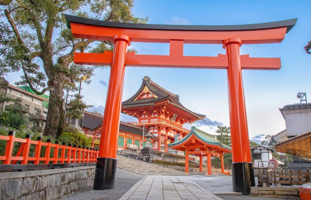 Large vermilion torii gate framing the entrance to Fushimi Inari Shrine in Kyoto