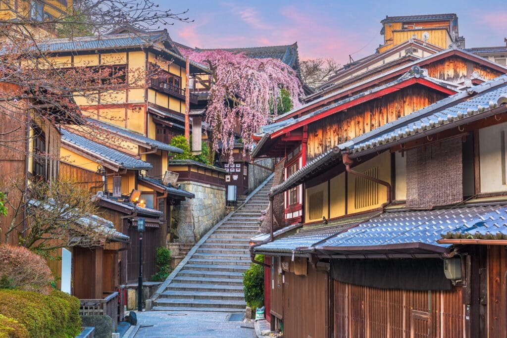 Traditional wooden buildings and stone steps in Kyoto's Higashiyama district with pink cherry blossoms