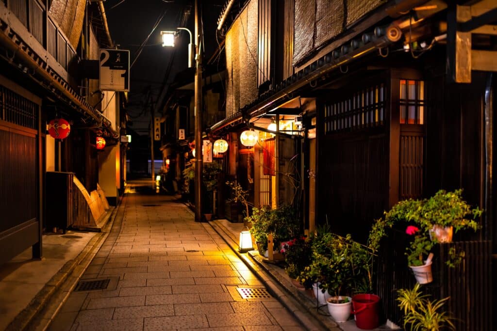 Quiet traditional street in Kyoto at night with wooden buildings and warmly illuminated lanterns