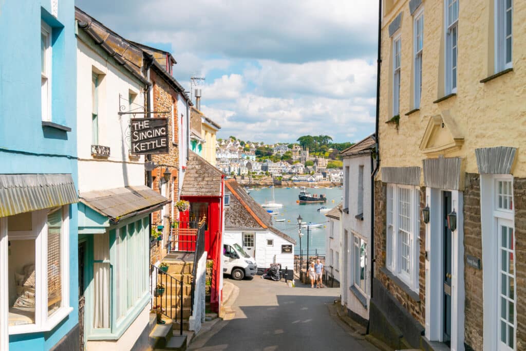 Narrow street lined with colourful historic buildings in Fowey, Cornwall, leading downhill towards the harbour