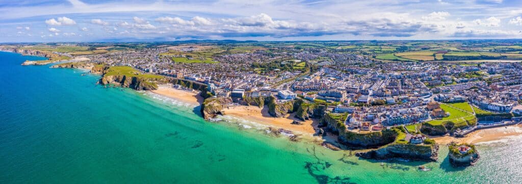 Aerial panorama of Newquay in Cornwall, showing sandy beaches, turquoise water, coastal cliffs and the seaside town