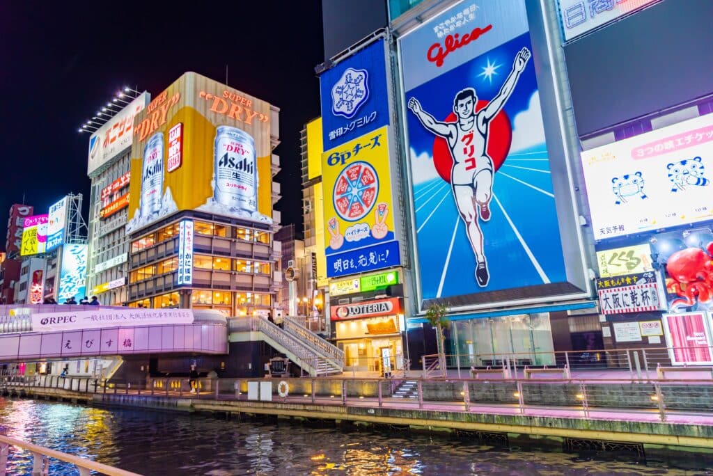 Famous Glico Running Man billboard and illuminated advertising signs beside Dotonbori Canal in Osaka at night