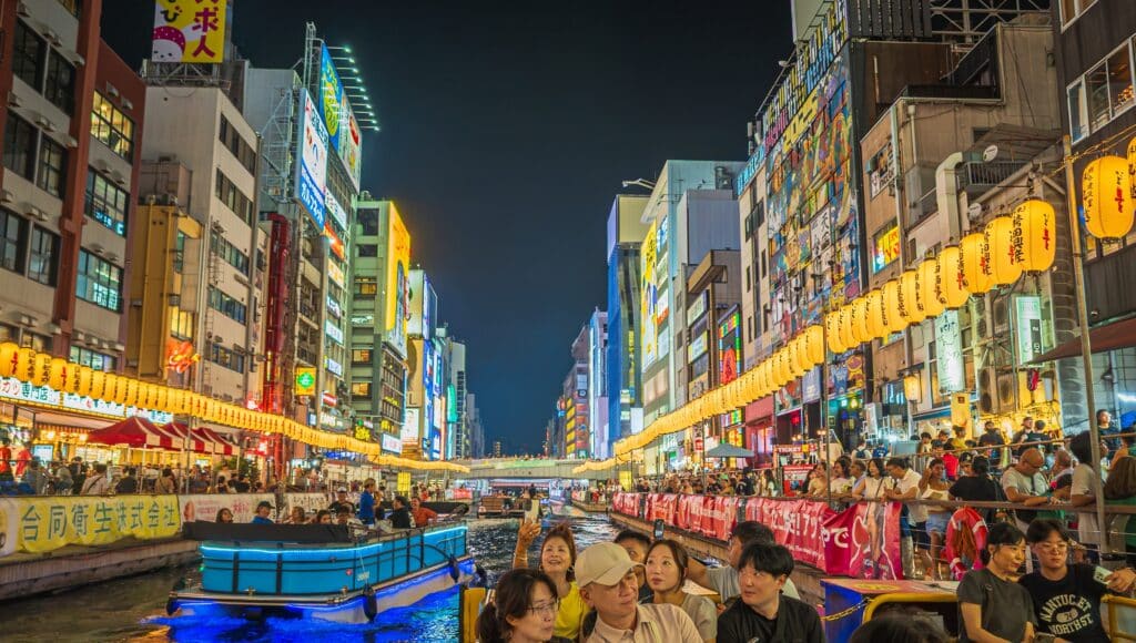Illuminated Dotonbori canal in Osaka with lanterns, restaurants, and visitors at night
